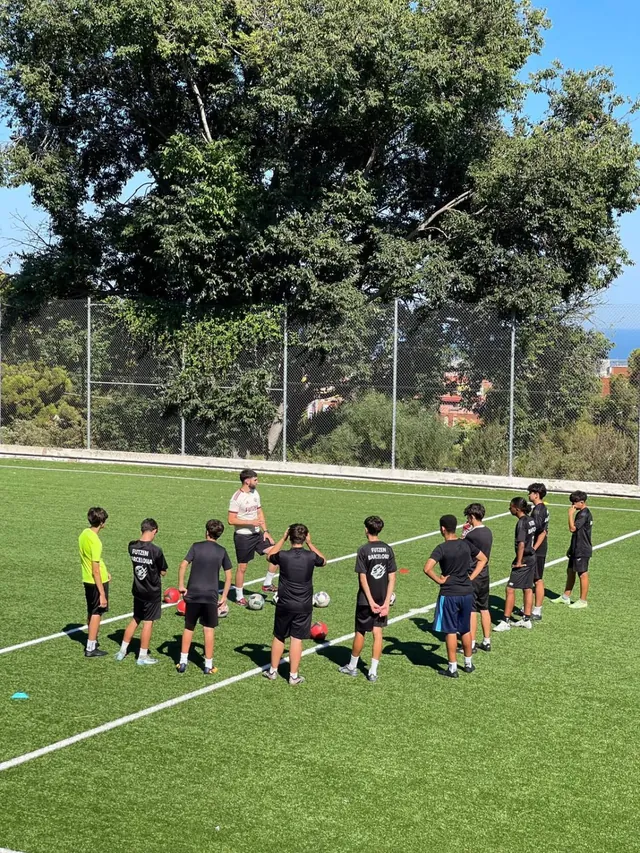 Un entrenador de FUTZEN explica un ejercicio a los jugadores en círculo