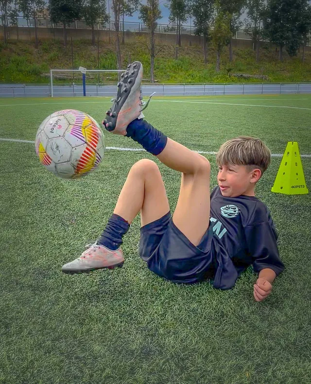 Un niño de FUTZEN controla el balón tumbado en el césped